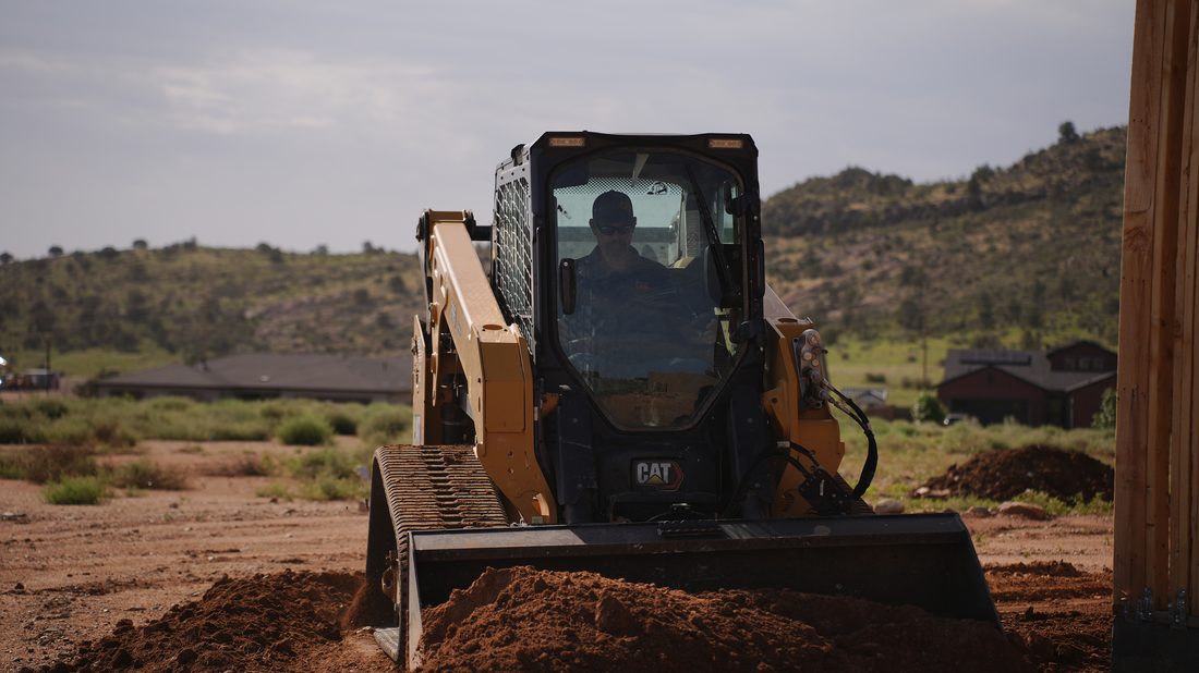 CAT skid steer operator moving soil on a Prescott-area lot