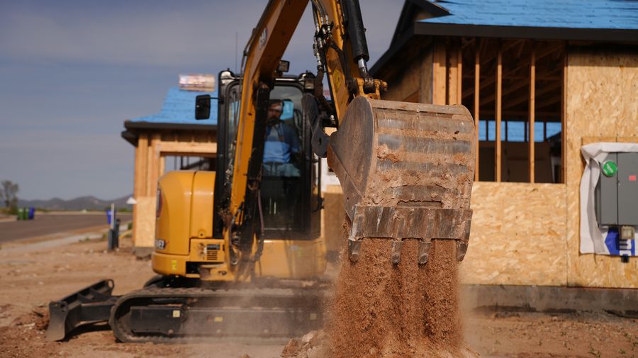 CAT excavator digging alongside a home under construction in the Prescott area