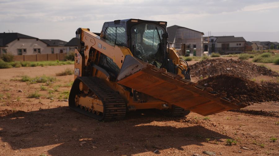 CAT skid steer with a grading blade leveling soil on a Prescott-area homesite